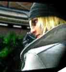 Man i vit kappa, med blont hår och svart mössa, snett bakifrån.